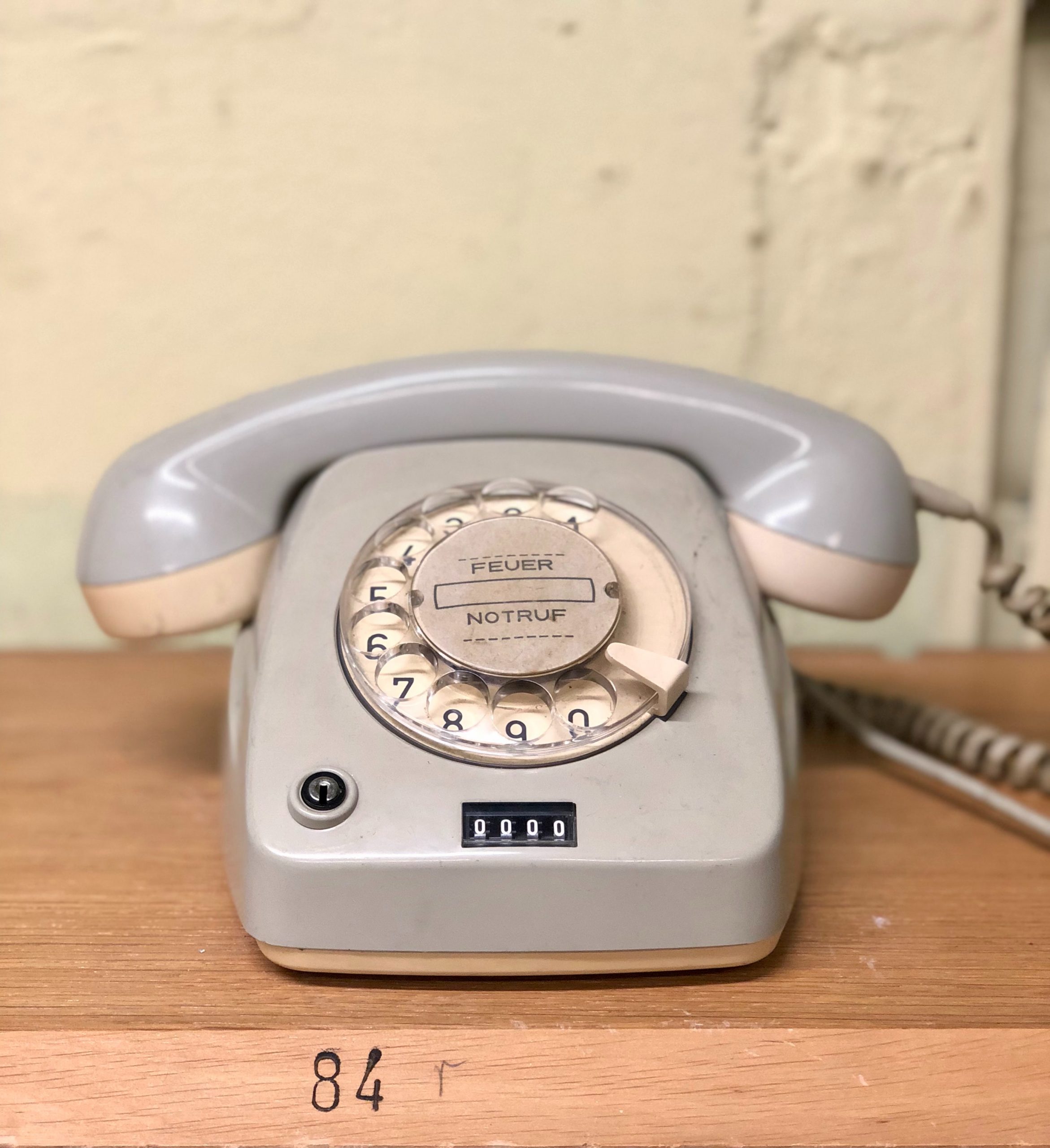 Nostalgisches weißes Wählscheibentelefon auf einem Holztisch