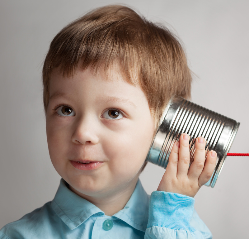 Kind spielt mit einem Dosentelefon als Symbol für Kommunikation